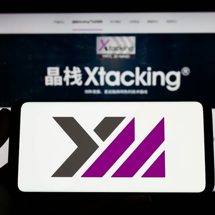 A smartphone showing the logo of YMTC is seen in front of a website detailing its Xtacking architecture.  Photo: Shutterstock 