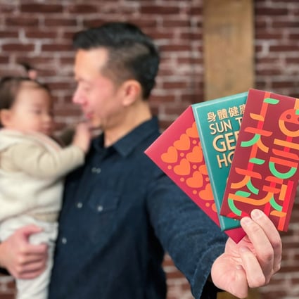 Chinese-Canadian Kevin Li holds up three Mission: Red Pocket envelopes and his daughter Ava in Vancouver. He asked three designers to make Lunar New Year greetings fun and easy to learn through modern lai see designs. Photo: Kevin Li