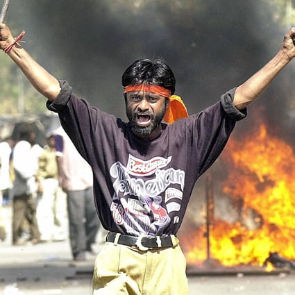 Indian Bajranj Dal activist armed with a iron stick shouts slogans against Muslims as material burns in Gujurat state in February 2002. Photo: AFP/File