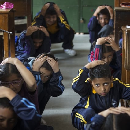 Nepalese school children crouch near their desks during an earthquake drill. The nation often experiences quakes; in 2015 around 9,000 people died in one. File photo:  EPA-EFE