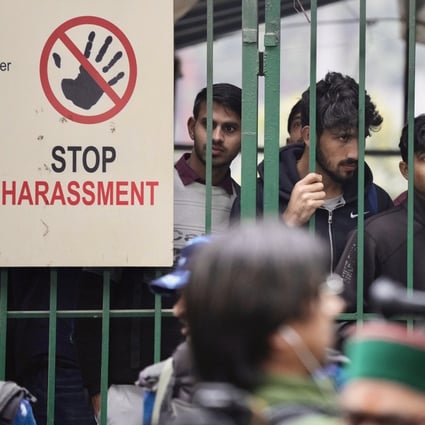 Students watch security personnel guard a gate of Jamia Millia Islamia university in New Delhi on Wednesday. Tensions escalated after a student group said it planned to screen a banned BBC documentary that examines Prime Minister Narendra Modi’s role during 2002 riots. Photo: AP