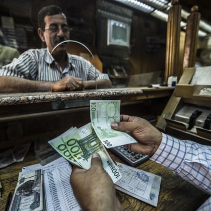 An employee counts banknotes at currency exchange in Cairo. The Egyptian pound has lost half its value against the US dollar since March, following a devaluation demanded as part of a US$3 billion IMF loan agreement. Photo: AFP