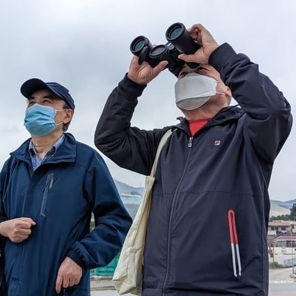 Lim Kian-sang (with binoculars) , 69, travelled with a friend to the border crossing at Heung Yuen Wai, which will open to the public on Monday, to try and spot his wife’s flat just inside mainland China. Photo: Kahon Chan