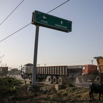 Commercial vehicles drive past a sign to Adani Port in Mundra, Gujarat, India. The ports-to-power conglomerate has repeatedly denied allegations made by a short-seller. Photo: Bloomberg