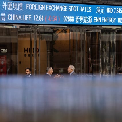 Pedestrians walk past a screen showing stock tickers outside the Exchange Square in Central, Hong Kong on March 14. Photo: EPA-EFE