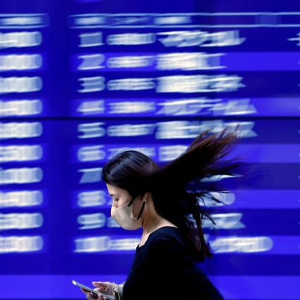 A woman walks past an electric monitor displaying recent stock price movements outside a bank in Tokyo on March 22. Since SVB plunged into crisis, Japan’s Topix Banks Index has lost 15 per cent. Photo: Reuters 