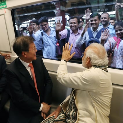 رئیس جمهور وقت کره جنوبی، مون جائه این، و نارندرا مودی، نخست وزیر هند، در حین سفر با مترو خود به کارخانه Samsung Electronics در اوتار پرادش، شمال هند، در 9 ژوئیه 2018 از تماشاگران استقبال می کنند. شرکت های کره جنوبی به طور فزاینده ای به دنبال هند به عنوان هدفی هستند. سرمایه گذاری و گسترش  عکس: EPA-EFE