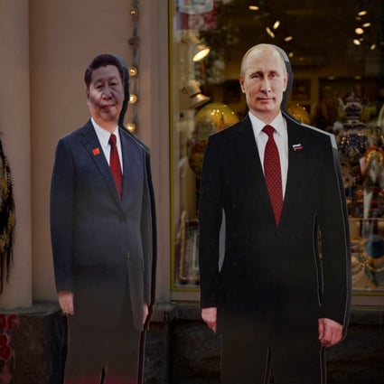 A woman stands next to cardboard cutouts of Russian President Vladimir Putin and Chinese President Xi Jinping in Moscow on June 14. Photo: AFP