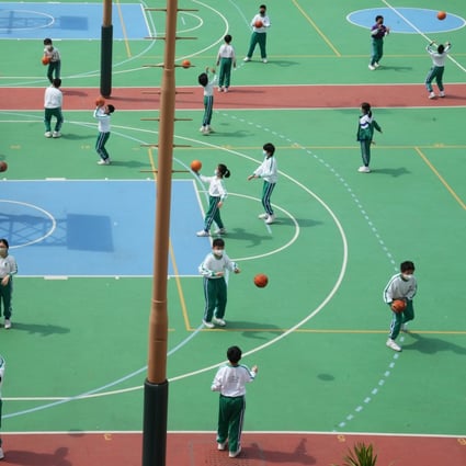 Schoolchildren play basketball at the height of the pandemic with masks on - but a survey has found many have kept wearing them because of worries about their looks. Photo: Sam Tsang