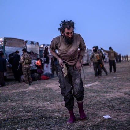A man suspected of belonging to Islamic State walks past members of the Kurdish-led Syrian Democratic Forces (SDF) just after leaving IS' last holdout of Baghouz. Photo: AFP