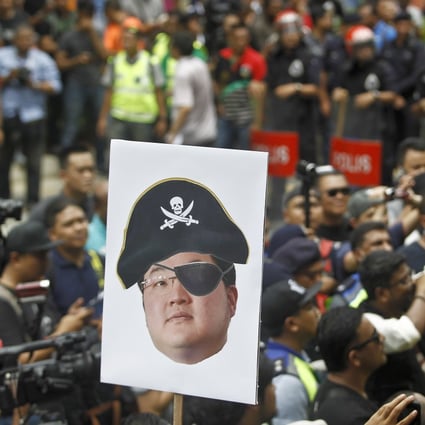 A portrait of Jho Low held aloft during a 2018 protest in Kuala Lumpur to call for his arrest over the alleged theft of billions from the Malaysian sovereign wealth fund 1MDB. Photo: AP