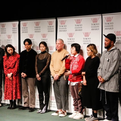 Akiko Shinoda (in red sweater) flanked by Nick Wooster (on her right) with Japanese designers at Tokyo Fashion Week.