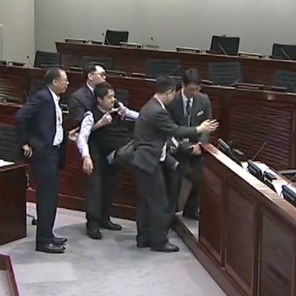 Security guards carry lawmaker Ted Hui from the meeting room on Monday. Photo: TVB