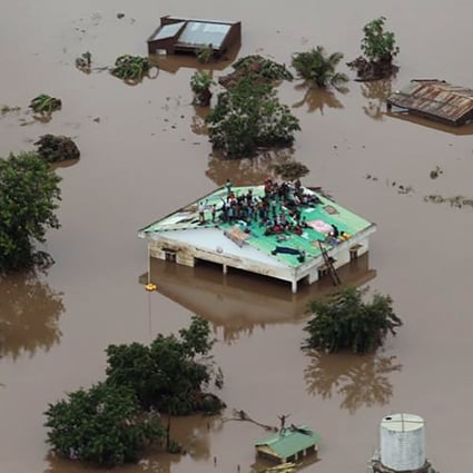 Groups of people stuck on rooftops with floodwaters up to window level in Beira. Photo: AFP