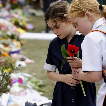 Children offer flowers on March 21 at a memorial site in Christchurch, New Zealand, for the 50 people who died in a gun attack on two mosques last week. In his online “manifesto”, the alleged gunman showed support for white supremacist and anti-Muslim, anti-Jewish, anti-immigrant ideology, as well as admiration for “non-diverse” nations. Photo: Kyodo