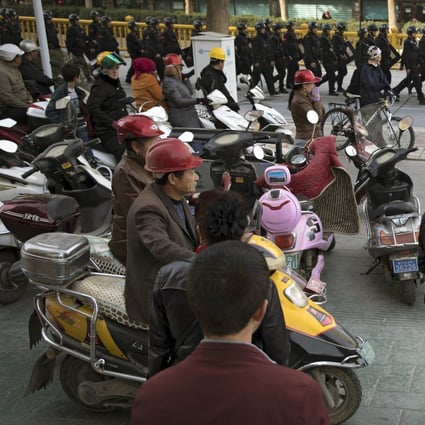 In this November 5, 2017, photo, residents watch a convoy of security personnel armed with batons and shields patrol through central Kashgar in China's Xinjiang region. The EU said it had rejected an offer last week by China’s foreign ministry to escort a tour of diplomats in Xinjiang starting Wednesday, but added that it remained open to an invitation at a later time. Photo: AP