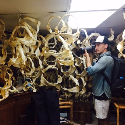 Rob Stewart photographs a collection of shark jaws in a sports fisherman’s home for his documentary Sharkwater Extinction.