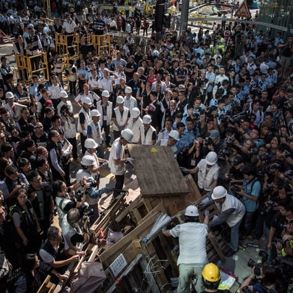Workers assist bailiffs in removing a barricade under a court injunction in Mong Kok on November 25, 2014. Photo: AFP