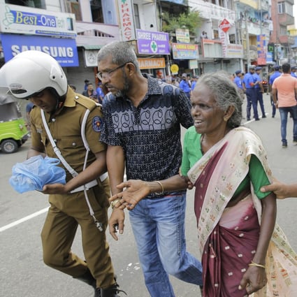 An elderly woman is helped near St Anthony's Shrine after a blast in Colombo, Sri Lanka. Photo: AP