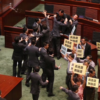 On July 3, 2014, lawmaker Wong Yuk-man (top) threw a glass and documents at chief executive Leung Chun-ying during a question-and-answer session in the Legislative Council. Divisive politics in Hong Kong predated the divisive Occupy protests that would start in September 2014. Photo: K.Y. Cheng