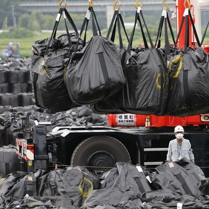 Workers move waste containing radiated soil, leaves and debris from the decontamination operation at a storage site in Naraha town. Photo: Reuters