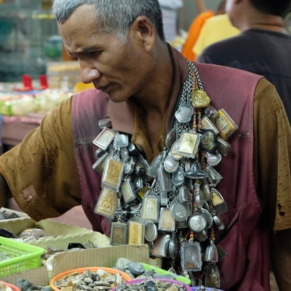 His clothes old and frayed, Kob Ladkrabang, a Thai amulet enthusiast, looks for a new acquisition at a Bangkok amulet market to add to his collection of 10,000. “I like amulets,” he says. Photo: Tibor Krausz