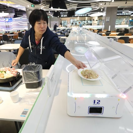 A diner at a Hema restaurant in Shanghai takes her dish after it is delivered by a robot. Photo: Simon Song