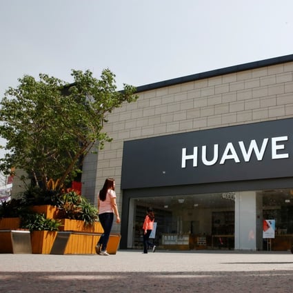 A woman looks at her phone as she walks past a Huawei shop in Beijing. Photo: Reuters