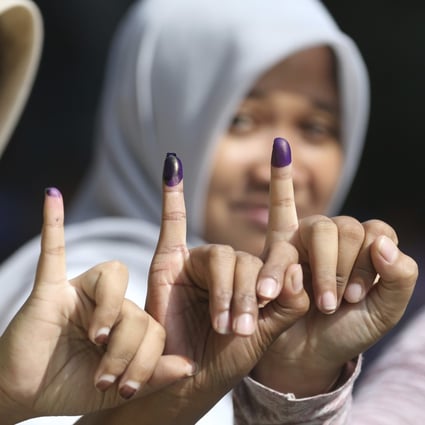 Muslim women show their ink-stained fingers after voting in Jakarta. Photo: AP