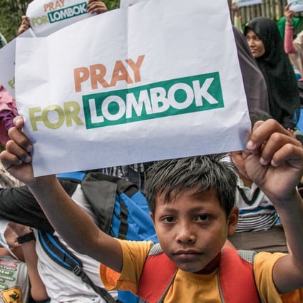 A child holds up a placard that reads “pray for Lombok” following the earthquake in August 2018. Photo: AFP