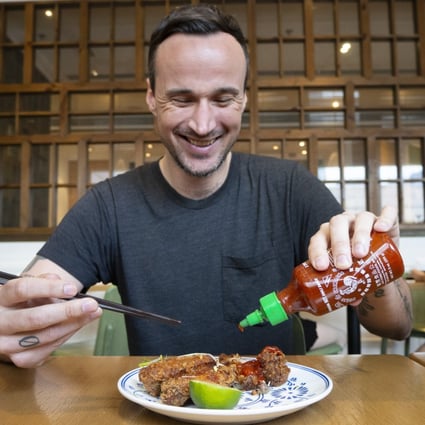 SCMP reporter Patrick Blennerhassett puts some Sriracha hot sauce on his chicken wings at Nha Trang restaurant, Times Square, Hong Kong. Photo: Antony Dickson