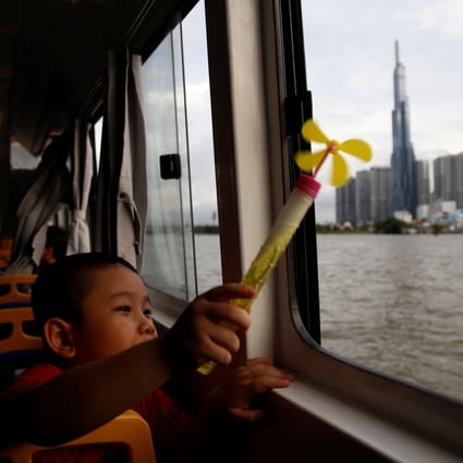A a child on a Saigon waterbus brandishes a pinwheel as he passes Landmark 81, Vietnam’s tallest building, in Ho Chi Minh City on June 6. While Vietnam has enormous potential for wind and solar power generation, funding for coal-power electricity plants under China’s Belt and Road Initiative could derail its renewable energy push. Photo: Reuters