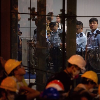 Officers stand inside the police headquarters in Wan Chai after the complex was blockaded by protesters calling for the complete withdrawal of the government’s extradition bill. Photo: Bloomberg