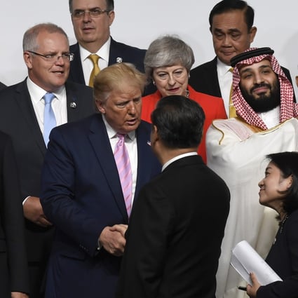 US President Donald Trump (centre) shakes hands with his Chinese counterpart Xi Jinping before a group photo at the G20 summit in Osaka on Friday. Photo: AP