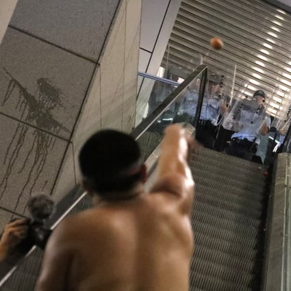 A protester throws an egg at officers at the police headquarters in Wan Chai. Photo: Felix Wong