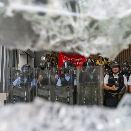 Riot police watch as crowds smash the doors of the Legislative Council. Photo: Sam Tsang