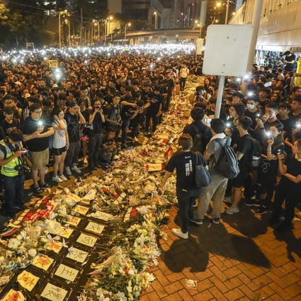 Protesters stand by flower bouquets on June 16 and offer prayers for a man who fell from Pacific Place mall in Admiralty and died while protesting against Hong Kong’s extradition law. Photo: Dickson Lee