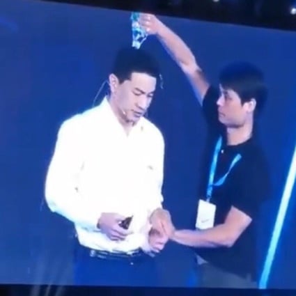 Baidu founder Robin Li looks shocked as a man from the audience pours a bottle of water over his head. Photo: Weibo