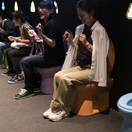 Visitors laugh as they jokingly motion to give a push while sitting on colourful toilet bowls at the Unko Museum in Yokohama. Photo: AP
