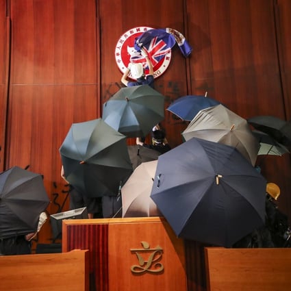 A protester covers the Hong Kong Special Administrative Region emblem with a British colonial flag during the storming of the Legco complex. Photo: Sam Tsang