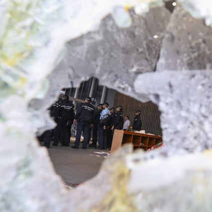 A group of Hong Kong police seen through broken glass after extradition bill protesters stormed the Legislative Council Chamber in Tamar. Photo: Felix Wong