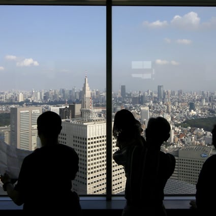 A family looks out of an office building window in central Tokyo. Photo: EPA