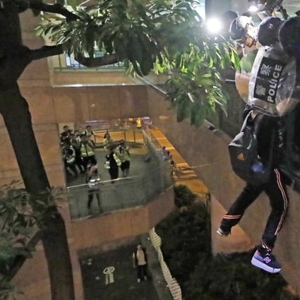 A suspect hangs perilously from a footbridge in Sheung Shui after police tried to speak to him. Photo: AP