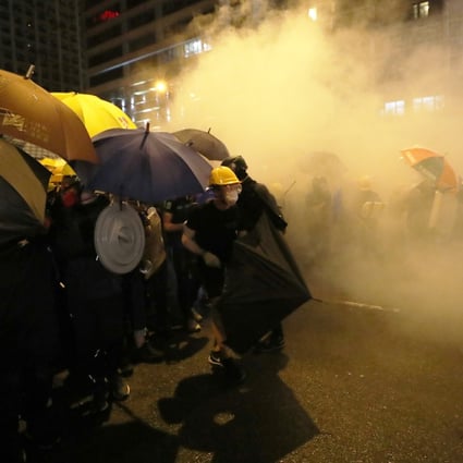 Protesters try to fight off the effects of tear gas fired by police on Sunday. Photo: Sam Tsang