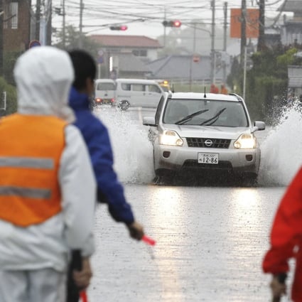 A car drives through a flooded road after heavy rain in Miyakonojo City. Photo: AP