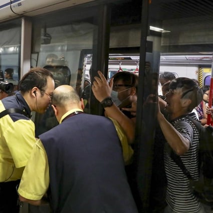 Protesters prevent the doors of a train closing as MTR staff try to stop them at Admiralty station. Photo: Nora Tam