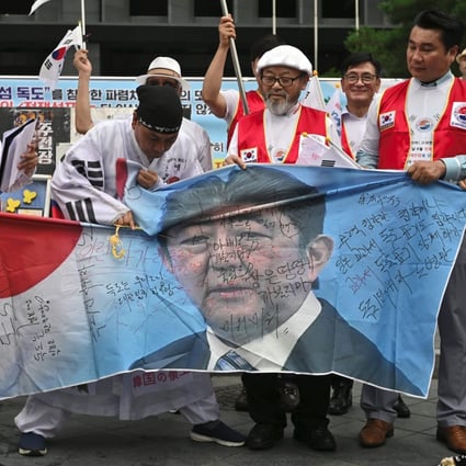 South Korean protesters cut a banner showing a picture of Japanese Prime Minister Shinzo Abe at a rally. Photo: AFP