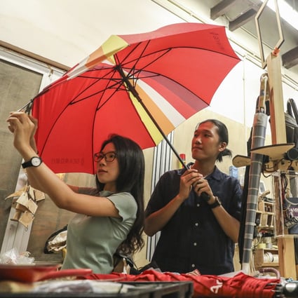 Winky Law and Jeffrey Kwong (left to right under red umbrella) repair a broken umbrella in a workshop at Aberdeen on July 17. Photo: Dickson Lee