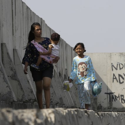 People walk near part of sea wall which prevents water flooding Jakarta. Photo: AP