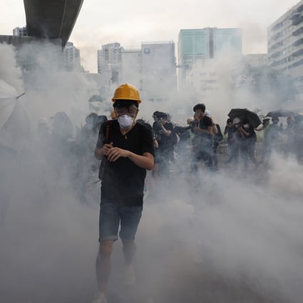 Protesters run through clouds of tear gas during clashes with police in Yuen Long. Photo: EPA-EFE